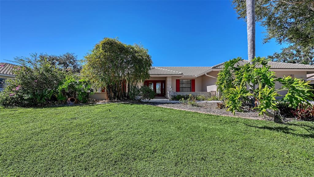 A single-story house with a beige exterior, tiled roof, and a large front lawn — 1109 DELACROIX CIRCLE, NOKOMIS, FL