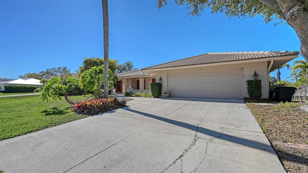 A single-story house with a beige exterior, a two-car garage, and a concrete driveway — 1109 DELACROIX CIRCLE, NOKOMIS, FL