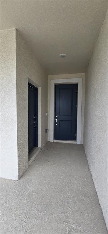 A covered entryway features two dark blue doors set against light-colored stucco walls and flooring — 1433 DEEPWATER CIR UNIT A, EAGLE LAKE, FL