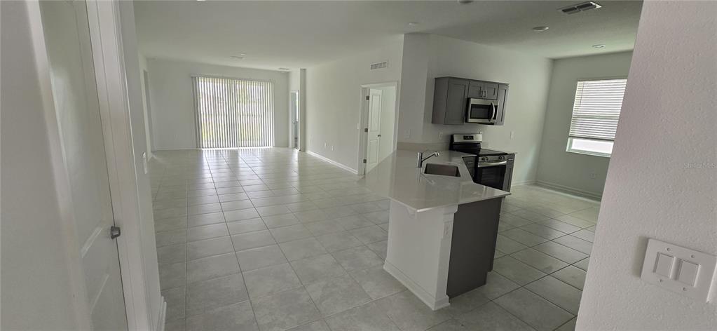 An open-concept kitchen with a quartz island overlooks a spacious tiled living area — 1433 DEEPWATER CIR UNIT A, EAGLE LAKE, FL