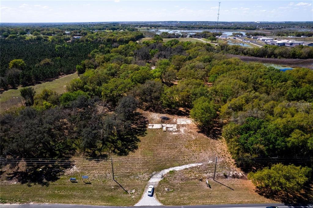 An aerial view shows a cleared lot with a concrete foundation surrounded by wooded areas — 18537 US HIGHWAY 27, MINNEOLA, FL