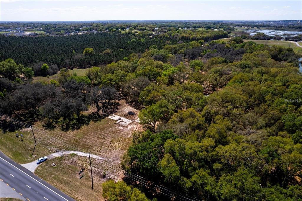 An aerial view shows a cleared lot with a concrete foundation beside a paved road — 18537 US HIGHWAY 27, MINNEOLA, FL