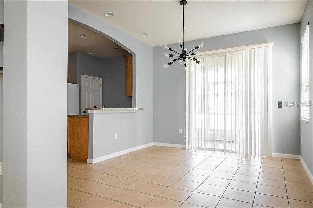 A dining area features light-colored tile flooring, a modern chandelier, and a sliding glass door — 14244 TURNING LEAF DRIVE, ORLANDO, FL