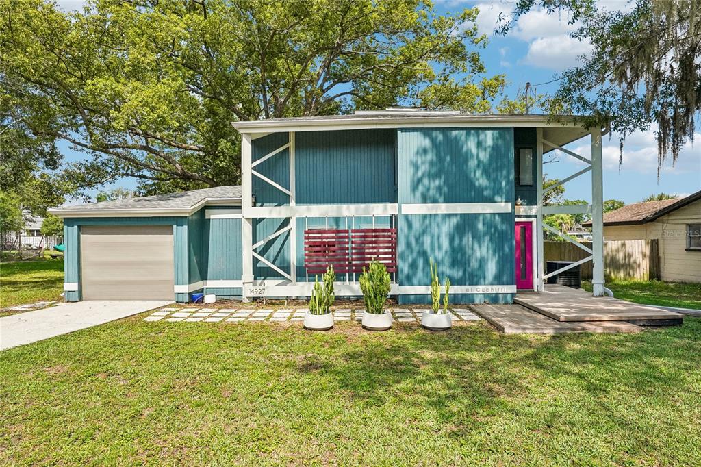 A two-story blue house with a garage, a pink front door, and three potted cacti — 14927 HARDY DRIVE W, TAMPA, FL