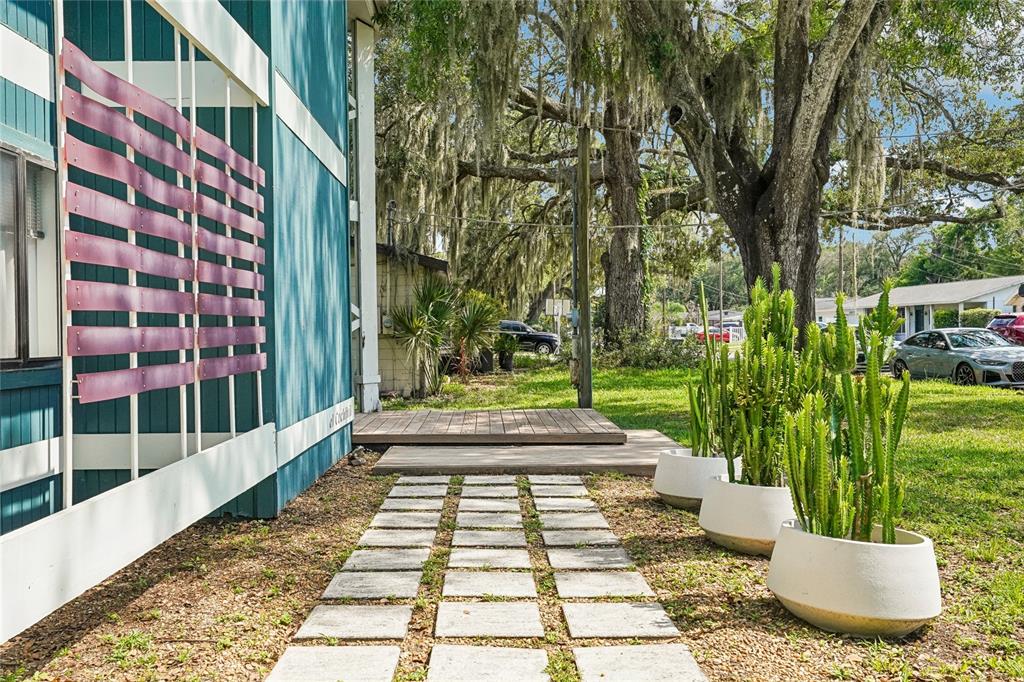 A teal house exterior features a wooden deck, stone paver path, and potted cacti — 14927 HARDY DRIVE W, TAMPA, FL
