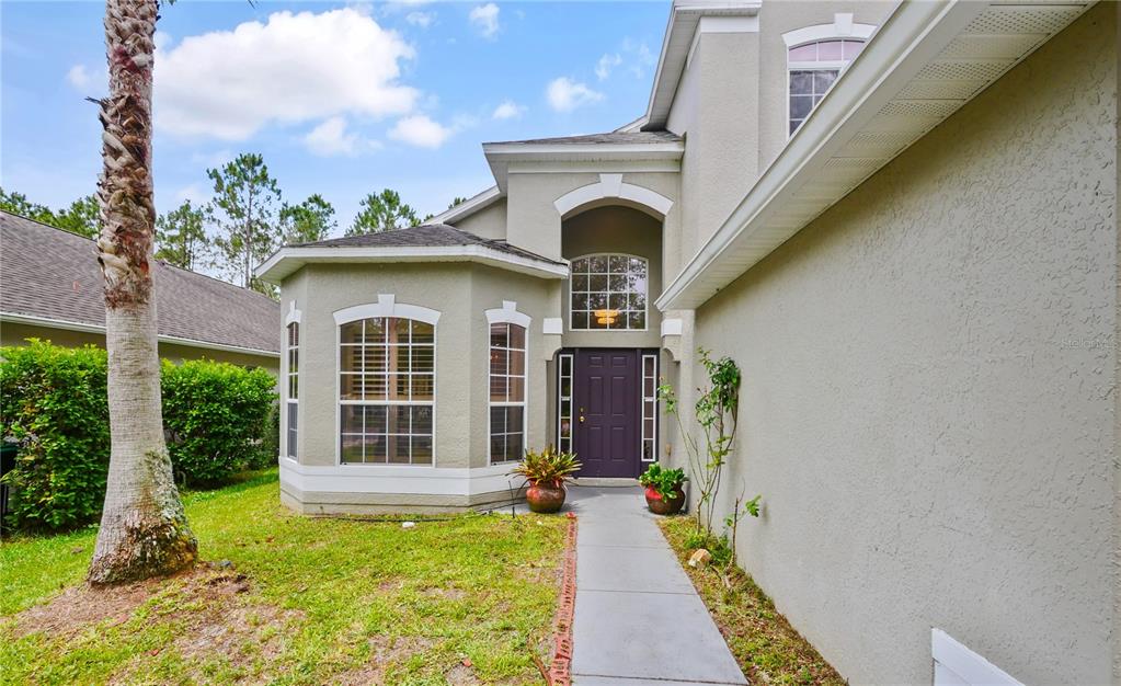 A beige two-story house features a purple front door and a concrete walkway — 4944 NATIVE DANCER LANE, ORLANDO, FL