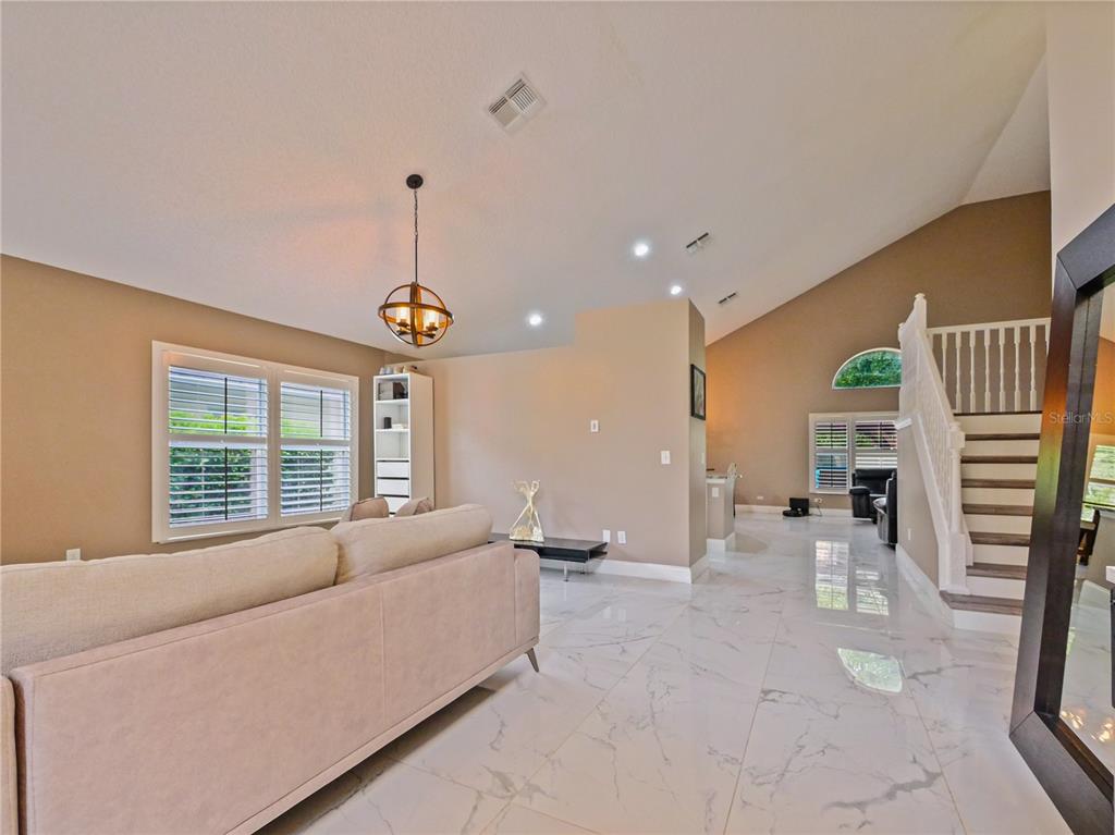 A living room features light-colored tile floors, a vaulted ceiling, and a staircase — 4944 NATIVE DANCER LANE, ORLANDO, FL