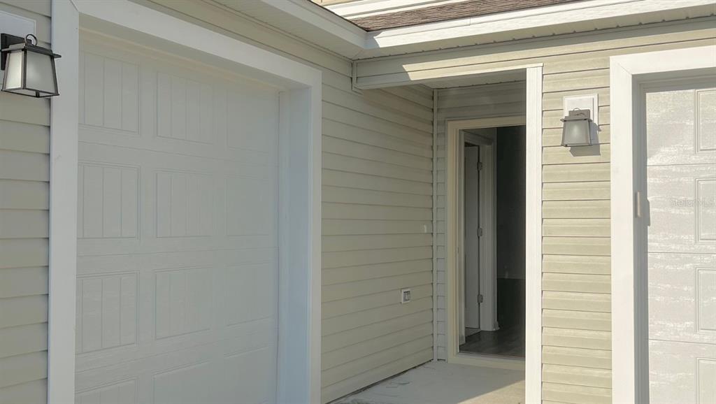 A view of a home exterior featuring a garage door, a front door, and siding — 6487 PETER LANE, THE VILLAGES, FL