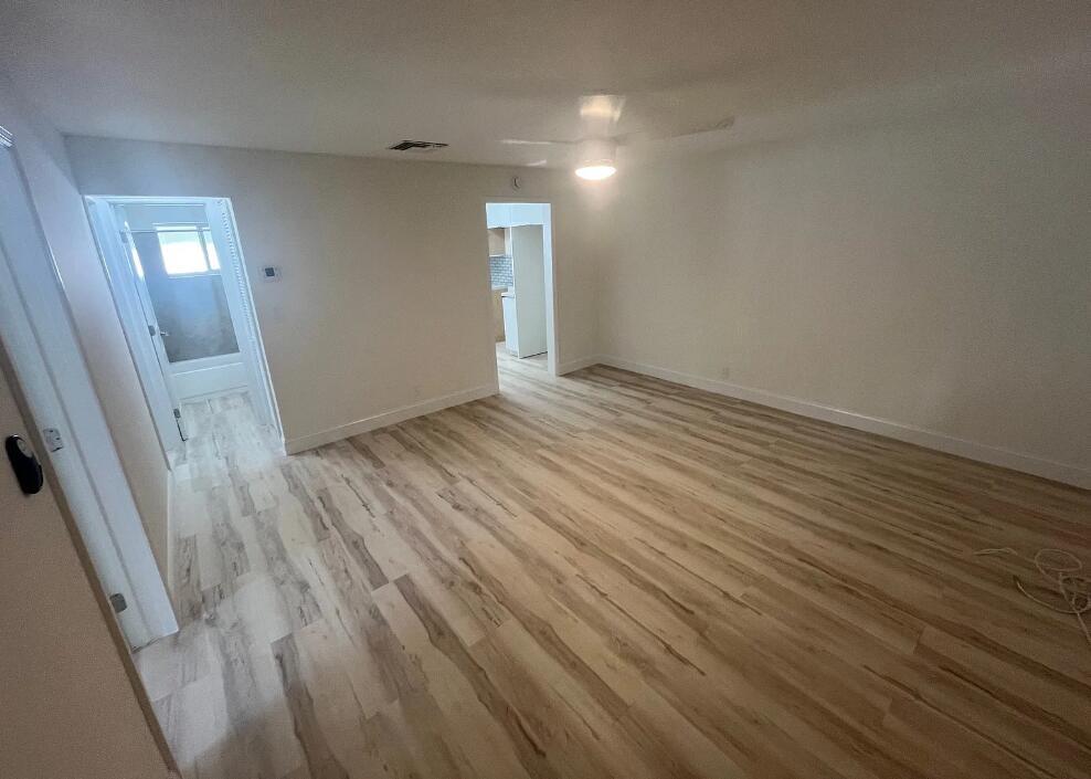 An empty room with light wood-look flooring, white walls, a ceiling fan, and two doorways — 240 NE 12th Street, Delray Beach FL 33444, DELRAY BEACH, FL