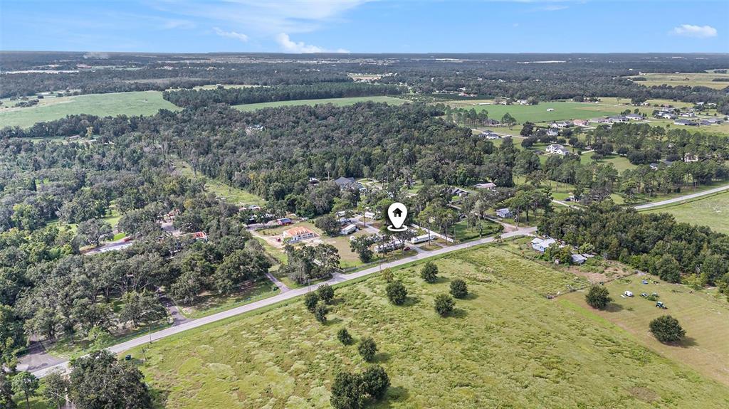 An aerial view shows a rural property with a house, trees, and surrounding open fields — 14638 TREELEAF LANE, DADE CITY, FL