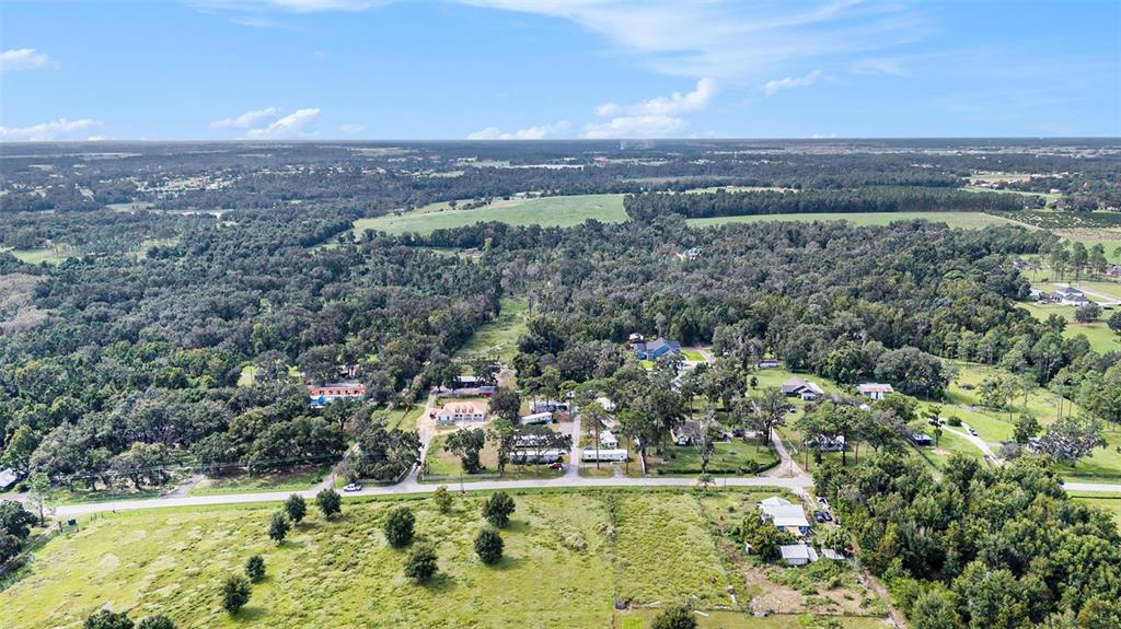 An aerial view shows a rural landscape with scattered houses, dense trees, and open fields — 14638 TREELEAF LANE, DADE CITY, FL
