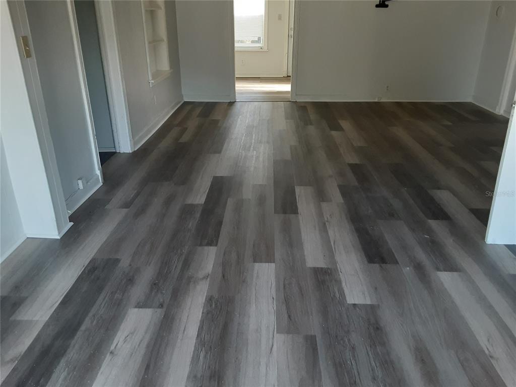 A room with gray wood-look plank flooring and white walls leading to another doorway — 312 FRANCES TERRACE, DAYTONA BEACH, FL