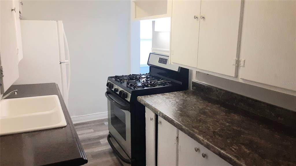 A kitchen features white cabinets, a black gas stove, and dark countertops — 312 FRANCES TERRACE, DAYTONA BEACH, FL