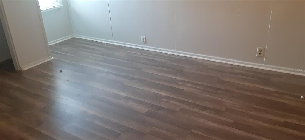 An empty room features light-colored walls, white baseboards, and wood-look laminate flooring — 312 FRANCES TERRACE, DAYTONA BEACH, FL