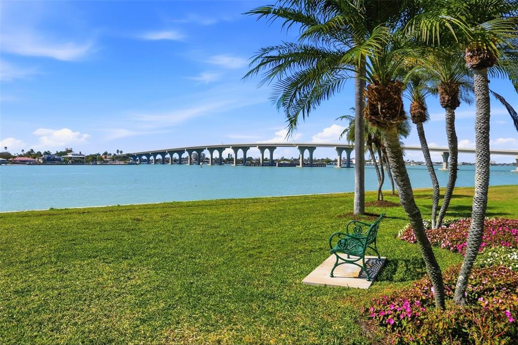 A green bench sits on a grassy lawn overlooking a bay with a large bridge — 6021 BAHIA DEL MAR CIRCLE UNIT 137, ST PETERSBURG, FL