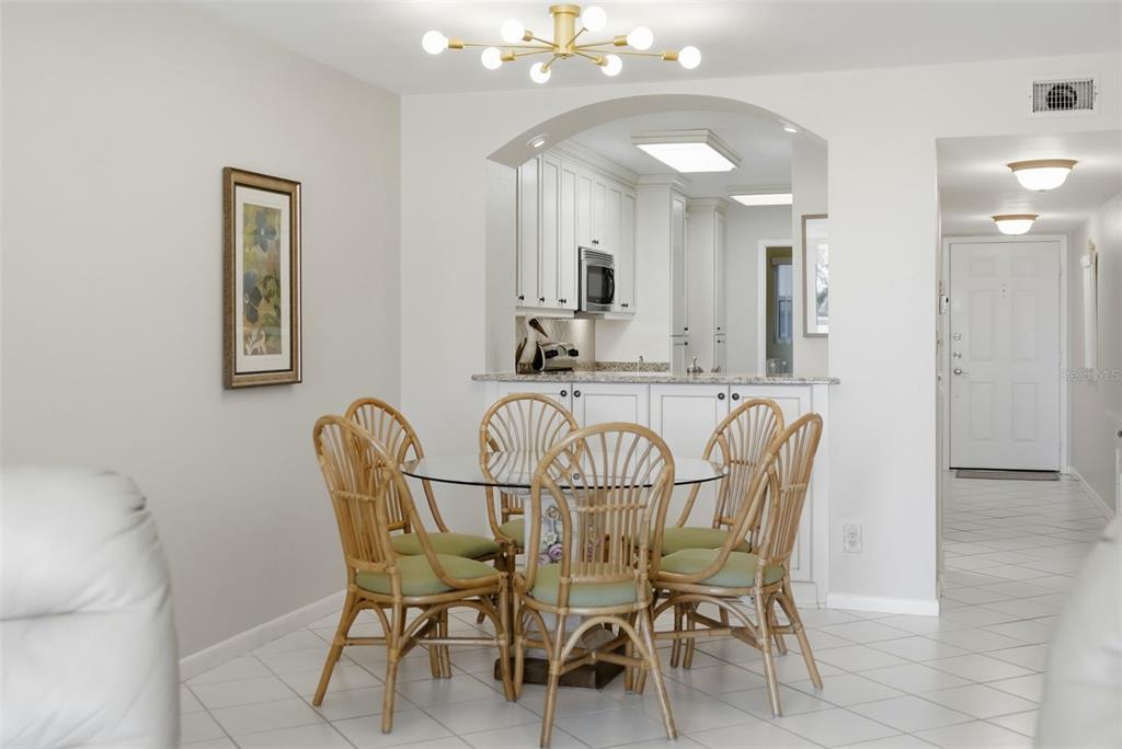 A dining area features a glass-topped table with four rattan chairs and a gold chandelier — 6021 BAHIA DEL MAR CIRCLE UNIT 137, ST PETERSBURG, FL