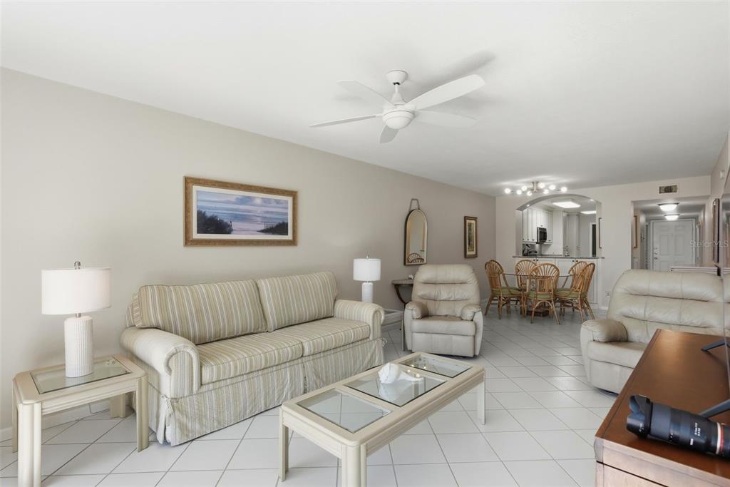 A living room with a striped sofa, two recliners, a coffee table, and dining area — 6021 BAHIA DEL MAR CIRCLE UNIT 137, ST PETERSBURG, FL