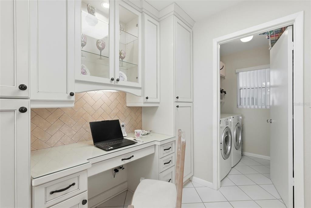 A home office desk with white cabinetry and a herringbone backsplash sits beside a laundry room — 6021 BAHIA DEL MAR CIRCLE UNIT 137, ST PETERSBURG, FL