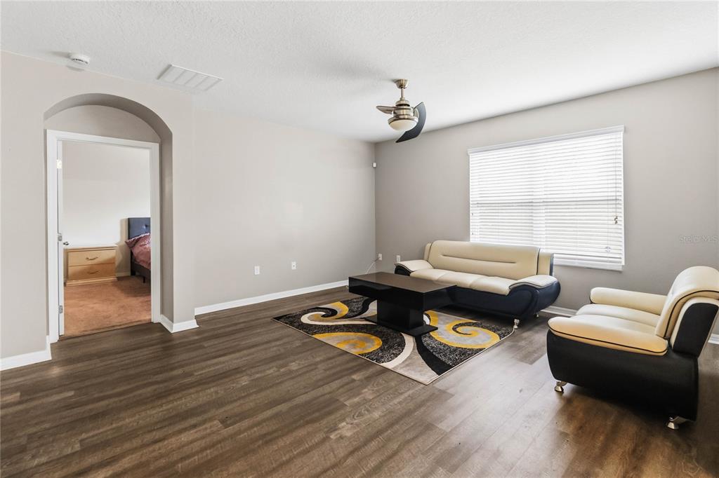 A living room features wood-look flooring, a ceiling fan, and two-toned cream and black furniture — 2318 SEQUOIA WAY, DAVENPORT, FL