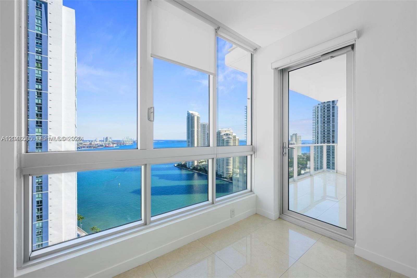 A bright room features floor-to-ceiling windows and a glass door leading to a balcony — 300 S Biscayne Blvd # 2612, Miami FL 33131, MIAMI, FL