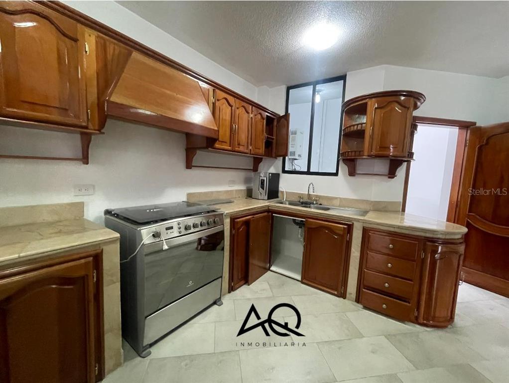 A kitchen features wooden cabinets, a stainless steel stove, and light-colored tiled countertops and floors — 2820 PEDRO VICENTE MALDONADO, LOJA/ECUADOR, OC