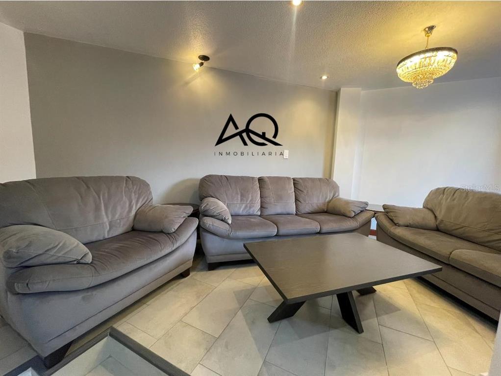 A living room features three gray sofas arranged around a dark square coffee table — 2820 PEDRO VICENTE MALDONADO, LOJA/ECUADOR, OC