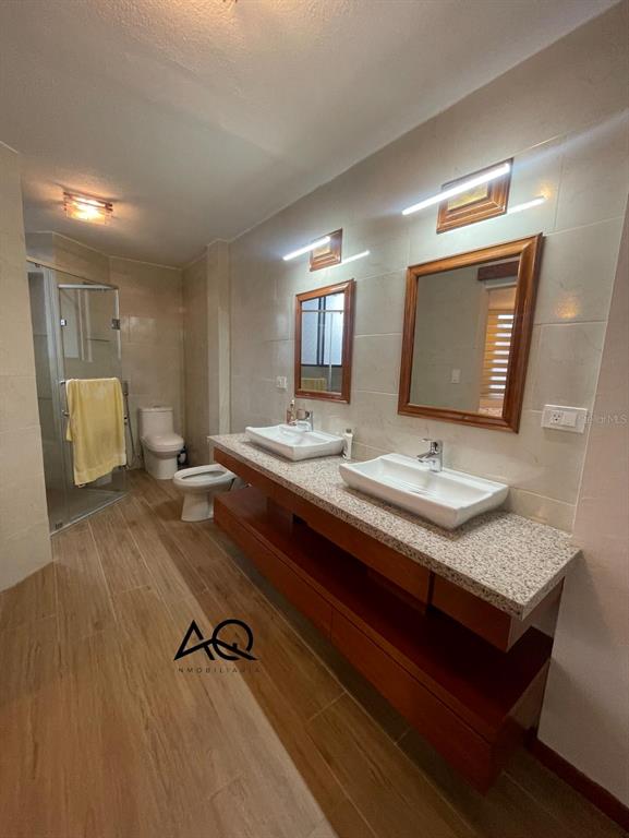 A bathroom features a double vanity with vessel sinks, wood cabinetry, and a glass shower — 2820 PEDRO VICENTE MALDONADO, LOJA/ECUADOR, OC
