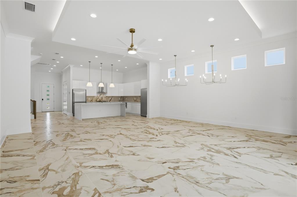 A modern open-concept kitchen and living area features white cabinetry and marble-patterned tile flooring — 7626 WHITEMARSH WAY, KISSIMMEE, FL