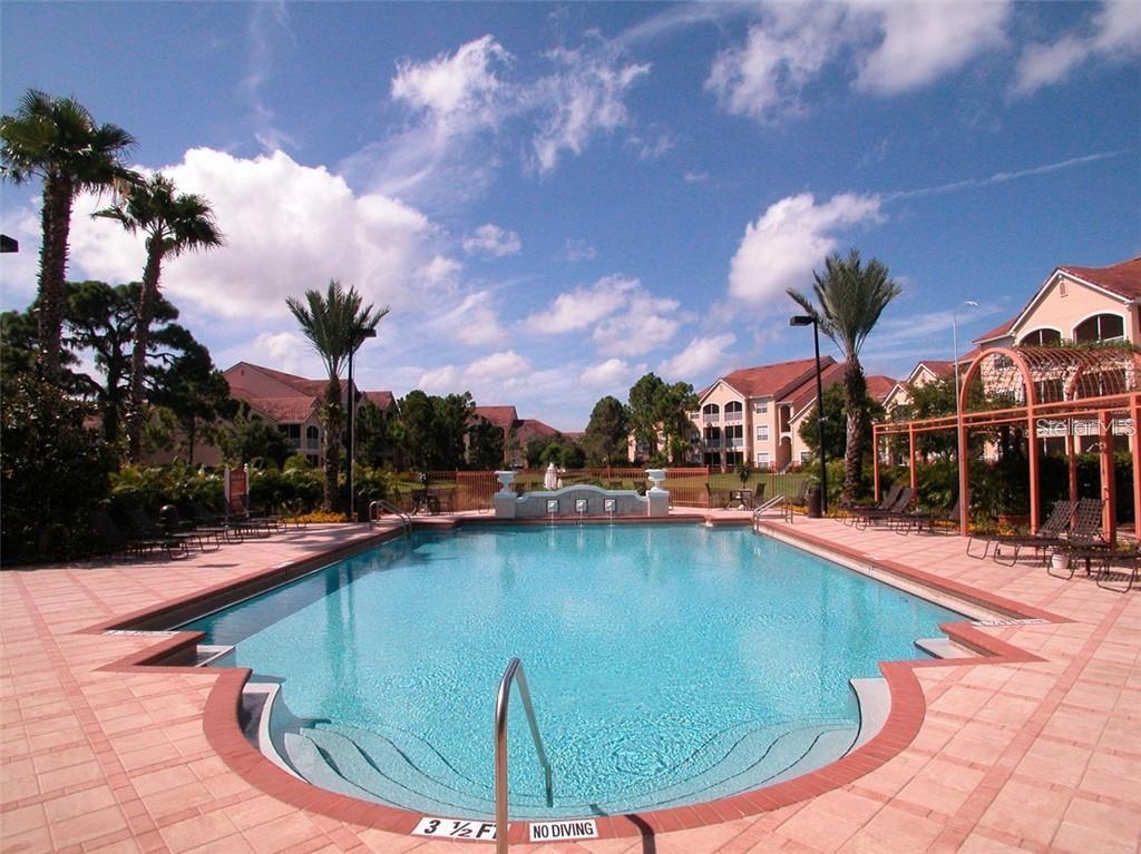 An outdoor swimming pool surrounded by a tiled deck, palm trees, and apartment buildings — 4126 CENTRAL SARASOTA PARKWAY UNIT 2012, SARASOTA, FL