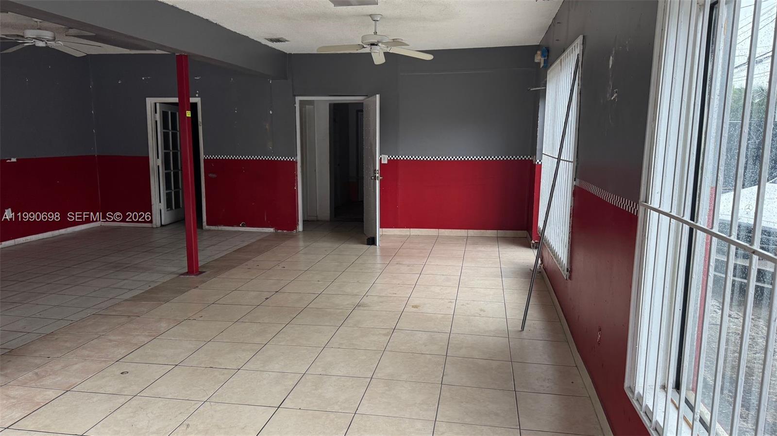 An empty room features tiled floors, gray and red walls, and a ceiling fan — 210 SW 22nd Ave, Miami FL 33135, MIAMI, FL
