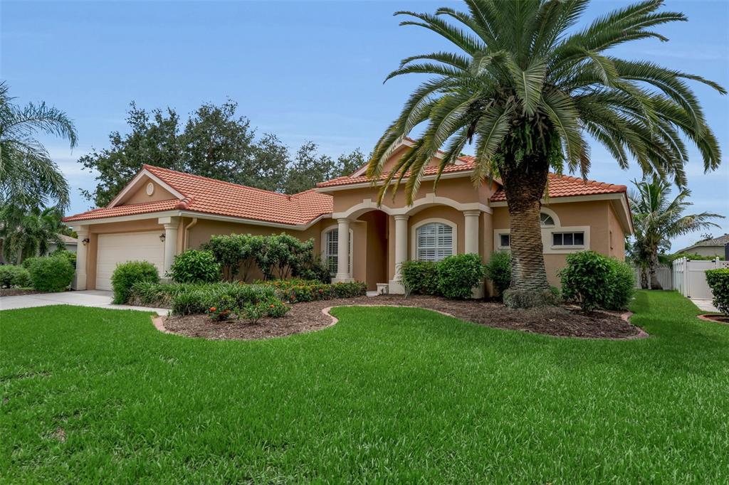 A single-story house with a tan stucco exterior, tile roof, and a large palm tree — 1036 OAK MEADOW LANE, OSPREY, FL