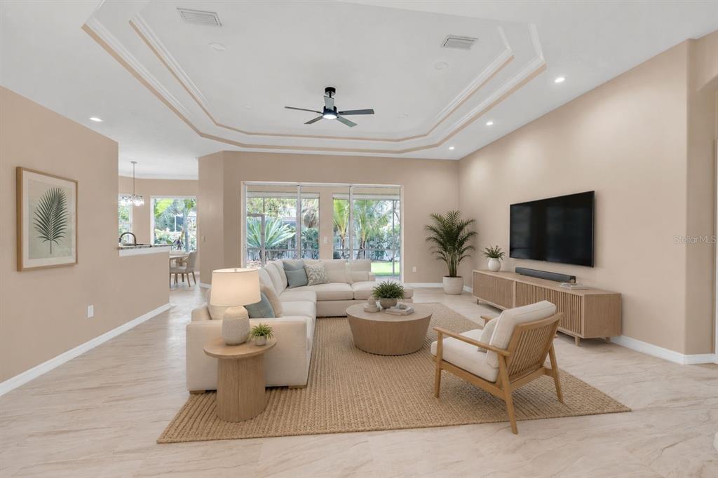 A living room features a tray ceiling, light tile floors, and a large sectional sofa — 1036 OAK MEADOW LANE, OSPREY, FL