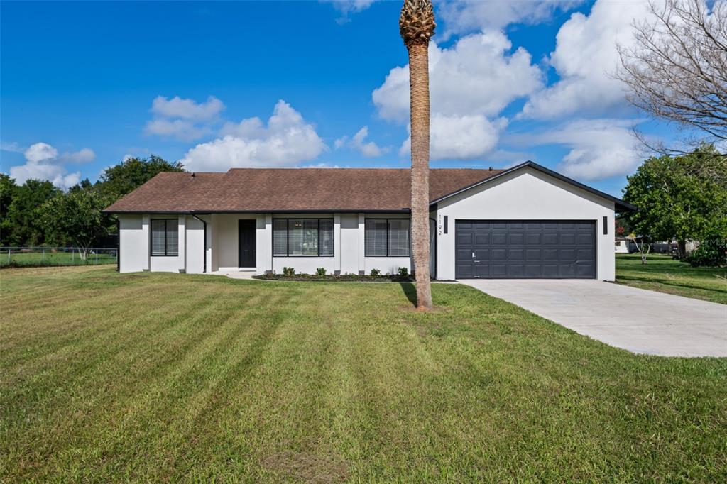 A single-story house with a white exterior, dark trim, and a two-car garage — 1192 LIZA STREET, ST CLOUD, FL