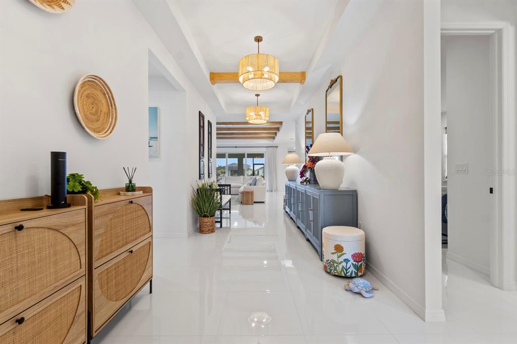 A bright, white-tiled hallway features wooden ceiling beams, rattan light fixtures, and a blue console — 16261 PRESERVATION BOULEVARD, PUNTA GORDA, FL