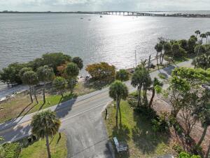 An aerial view shows a coastal road lined with palm trees next to a large bay — 4220 NE Indian River Dr. Drive # 2, Jensen Beach FL 34957, JENSEN BEACH, FL