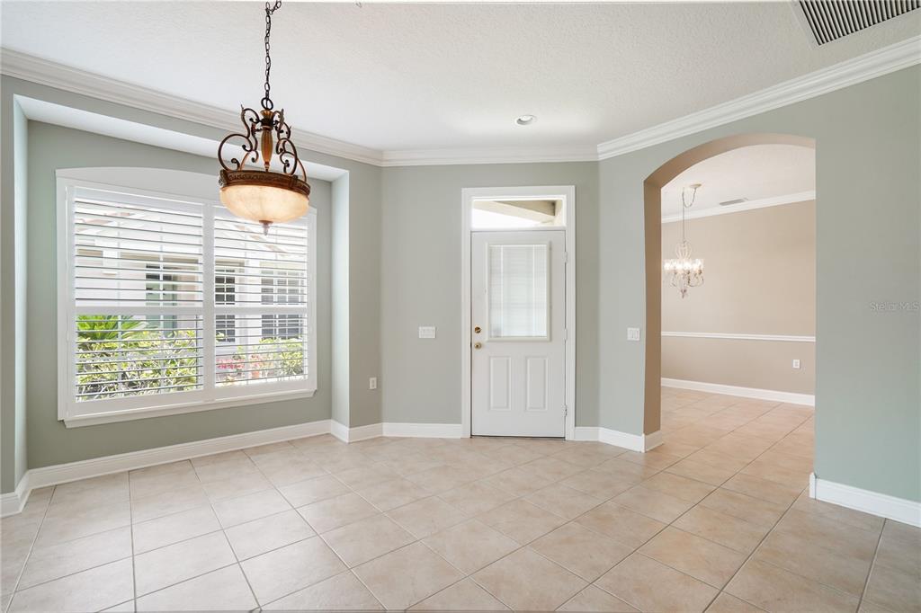 A dining area with tile floors, a chandelier, plantation shutters, and an arched entryway — 8336 TARTAN FIELDS CIRCLE, LAKEWOOD RANCH, FL