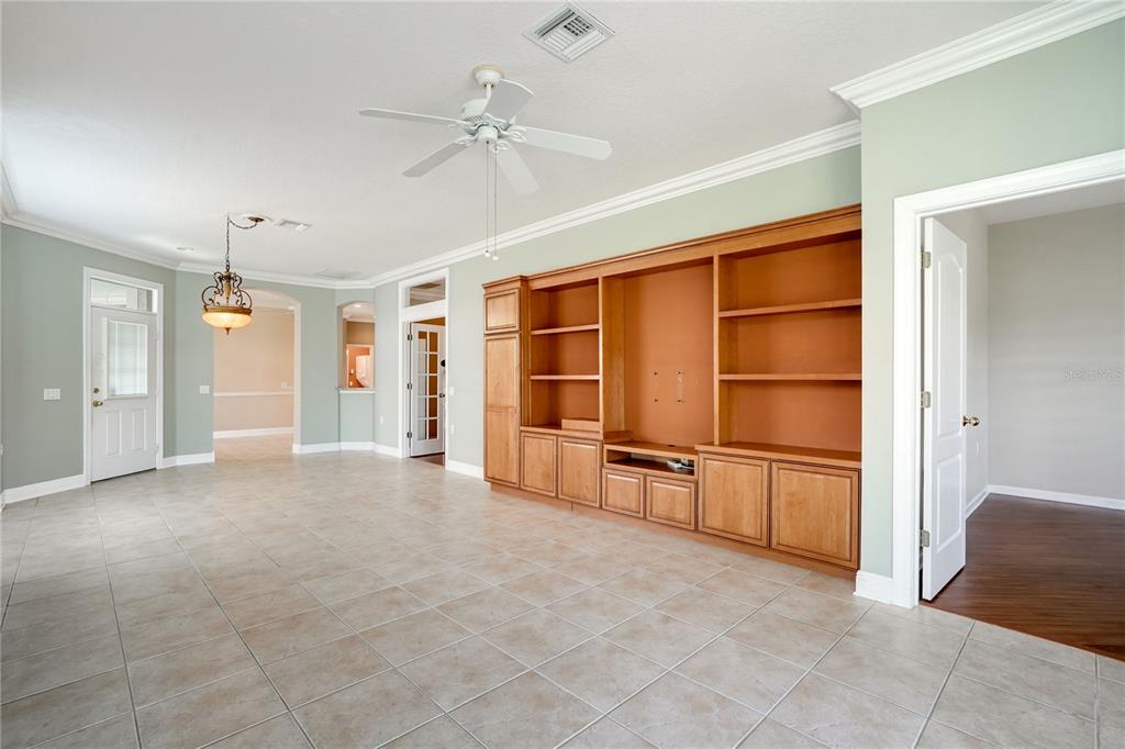 A living room features light green walls, tile flooring, a ceiling fan, and built-in wooden cabinetry — 8336 TARTAN FIELDS CIRCLE, LAKEWOOD RANCH, FL