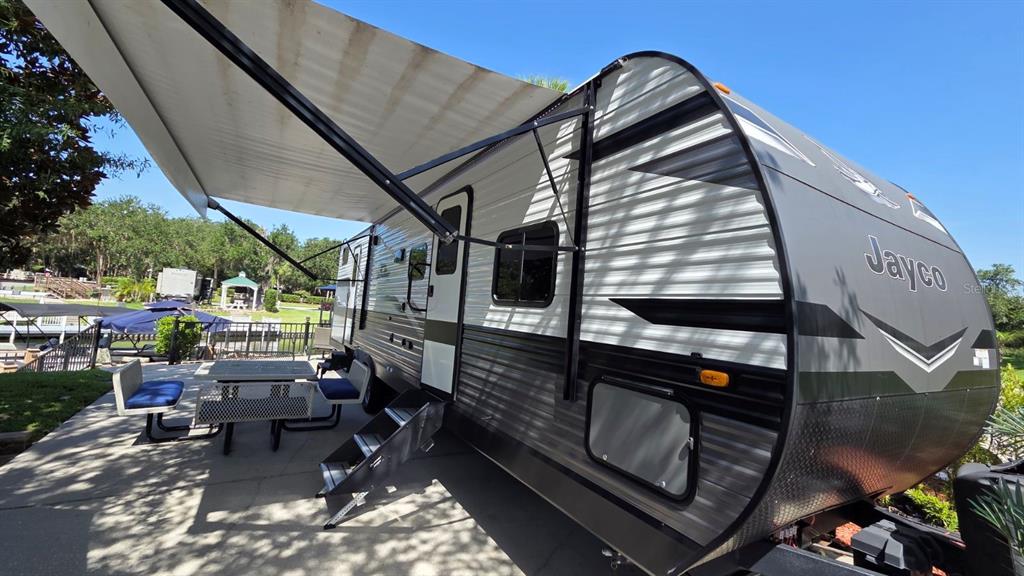 A Jayco travel trailer is parked on a concrete patio with its awning extended — 579 WATERWAY DRIVE, RIVER RANCH, FL