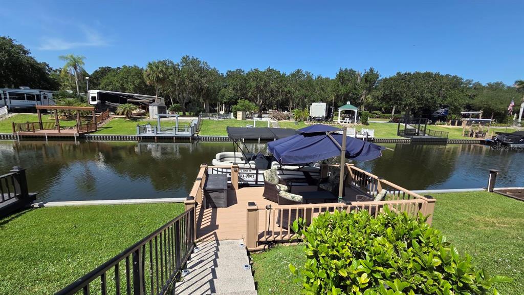 A wooden deck with a boat slip and canopy overlooks a canal lined with trees — 579 WATERWAY DRIVE, RIVER RANCH, FL
