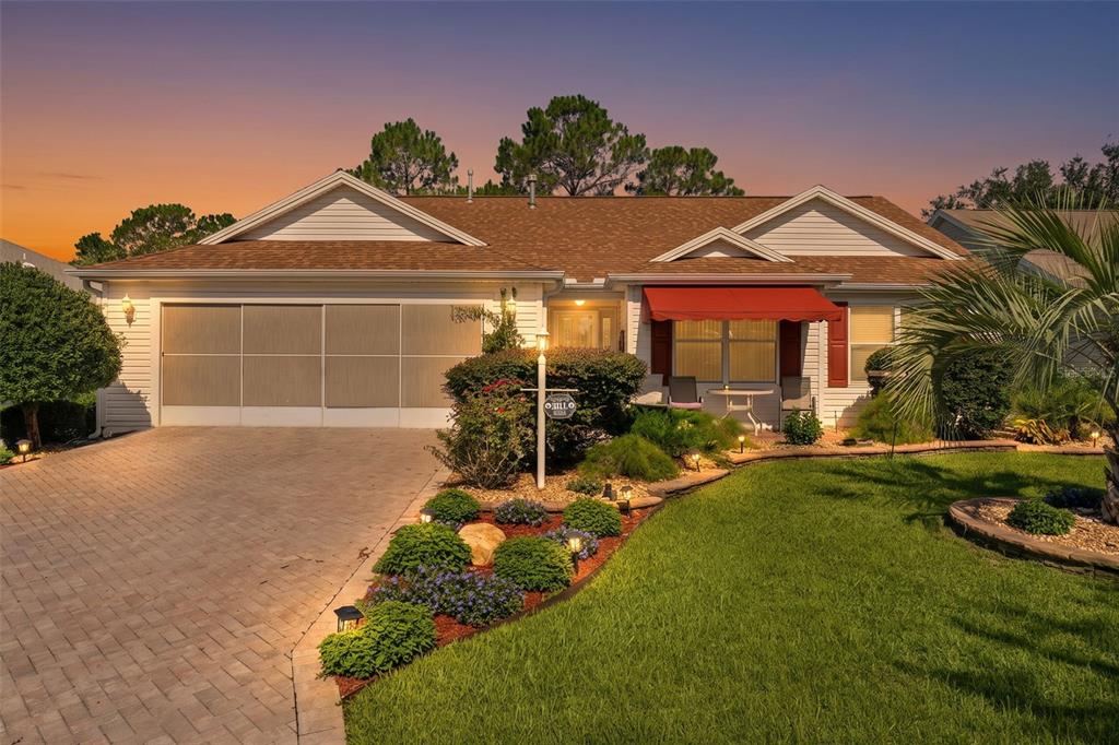 A single-story house with a paved driveway, a red awning, and landscaped front yard — 16846 SE 80TH BELLAVISTA CIRCLE, THE VILLAGES, FL