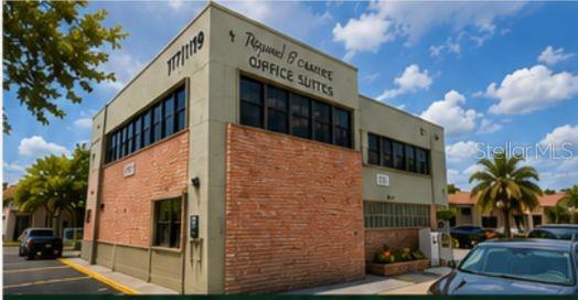 A two-story commercial office building features a brick facade and dark-framed windows under a sky — 117 N 5TH STREET, FORT PIERCE, FL