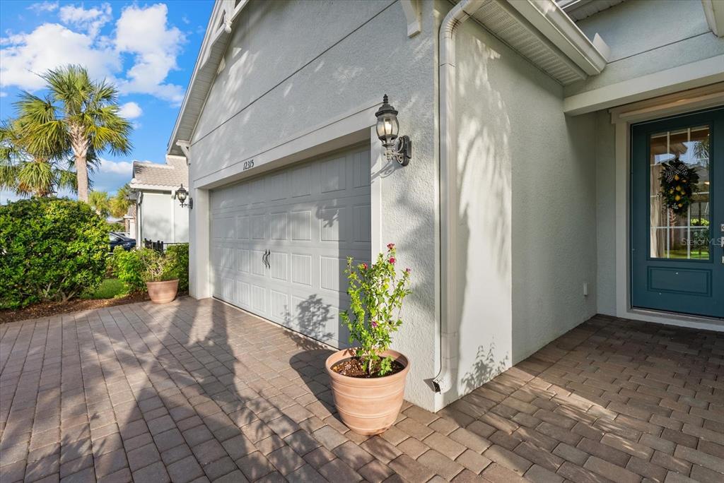 A paved driveway leads to a garage and a teal front door with a wreath — 12315 BLUE HILL TRAIL, BRADENTON, FL