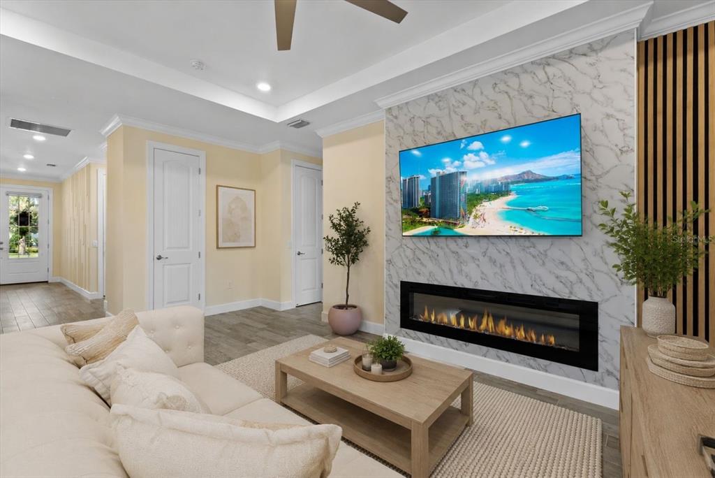 A living room features a marble-tiled fireplace wall, a mounted television, and light-colored furniture — 12315 BLUE HILL TRAIL, BRADENTON, FL