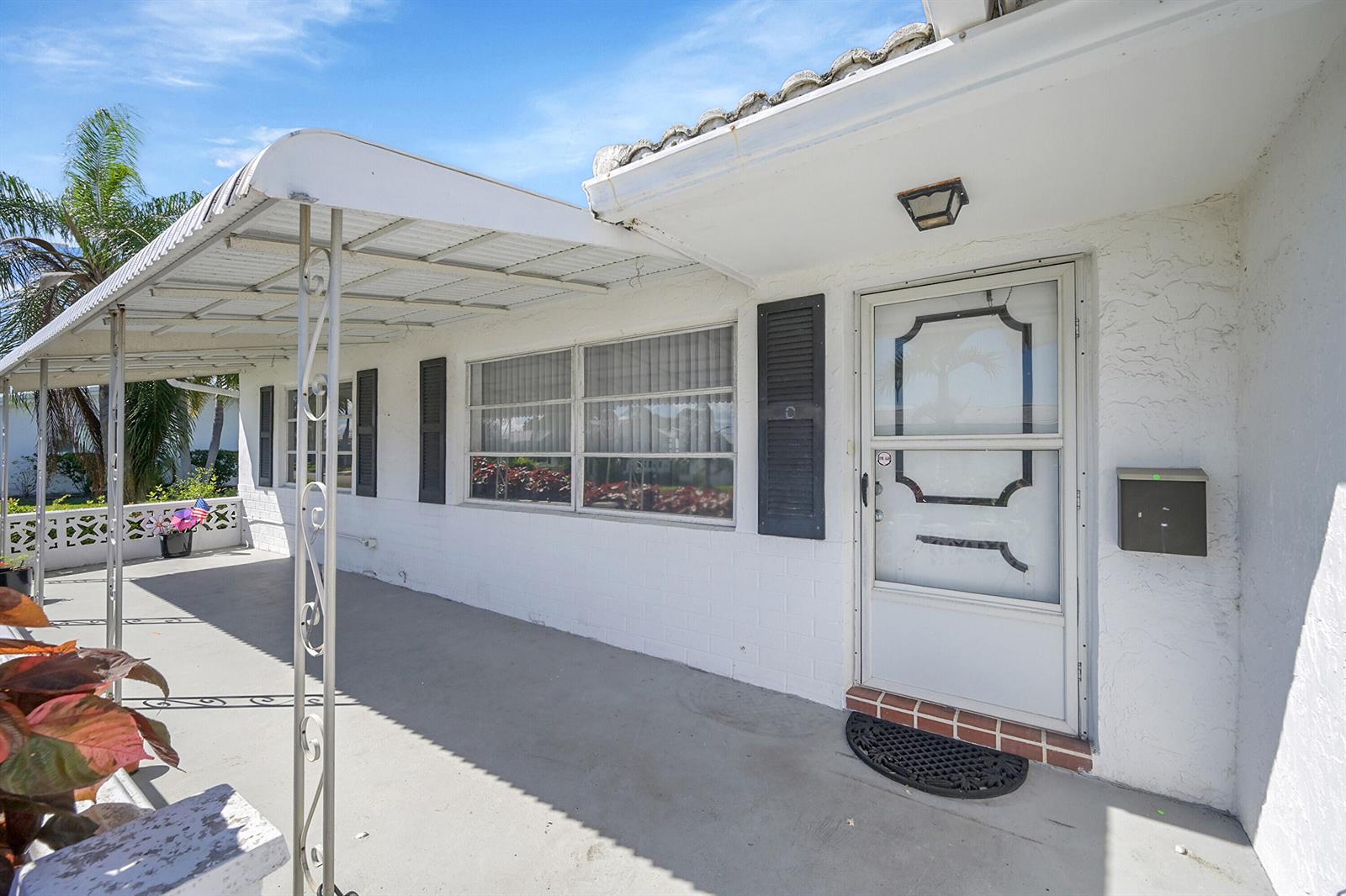 A white exterior house facade features a covered porch, a storm door, and shutters — 1515 SW 21st Street, Boynton Beach FL 33426, BOYNTON BEACH, FL
