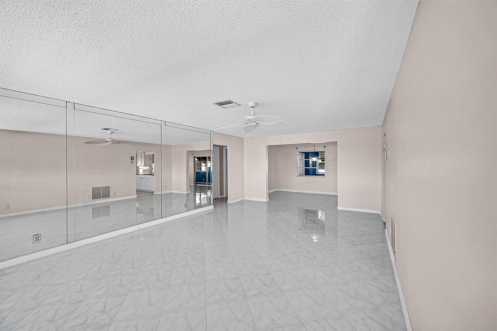 A spacious room with light-colored tile flooring, a mirrored wall, and a ceiling fan — 1515 SW 21st Street, Boynton Beach FL 33426, BOYNTON BEACH, FL