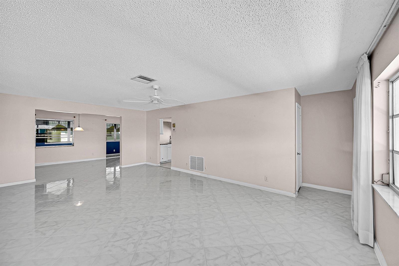 An empty living room features light-colored tile flooring, pale walls, and a white ceiling fan — 1515 SW 21st Street, Boynton Beach FL 33426, BOYNTON BEACH, FL
