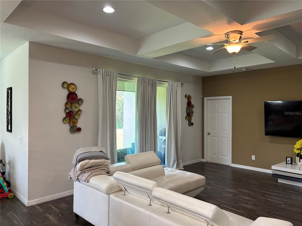A living room features a white sectional sofa, dark wood flooring, and a tray ceiling — 1727 BRASSIE COURT, KISSIMMEE, FL