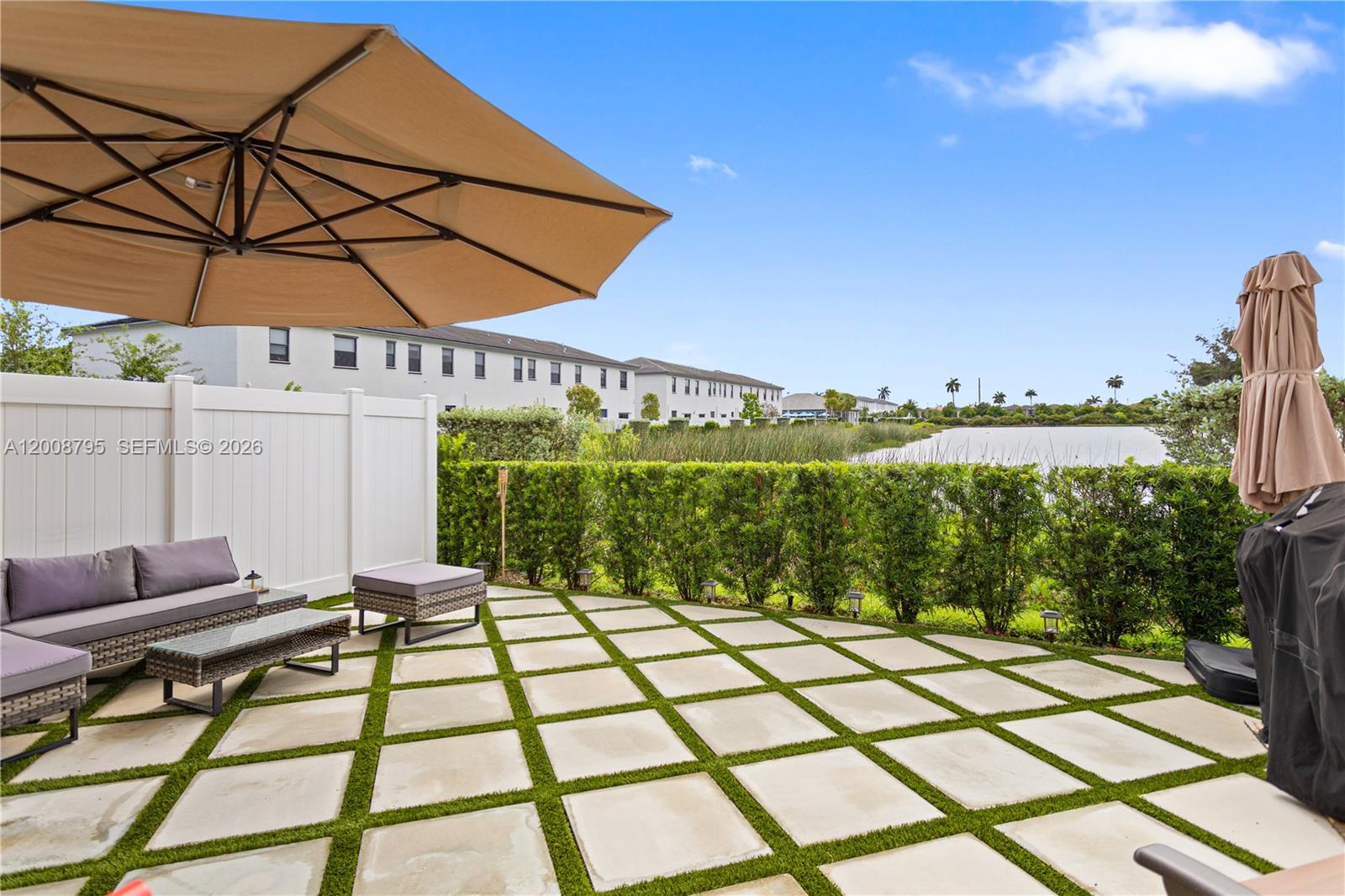 A patio features square pavers with grass inlays, outdoor furniture, and a view of a lake — 20478 NW 4th Ct, Miami Gardens FL 33169, MIAMI GARDENS, FL