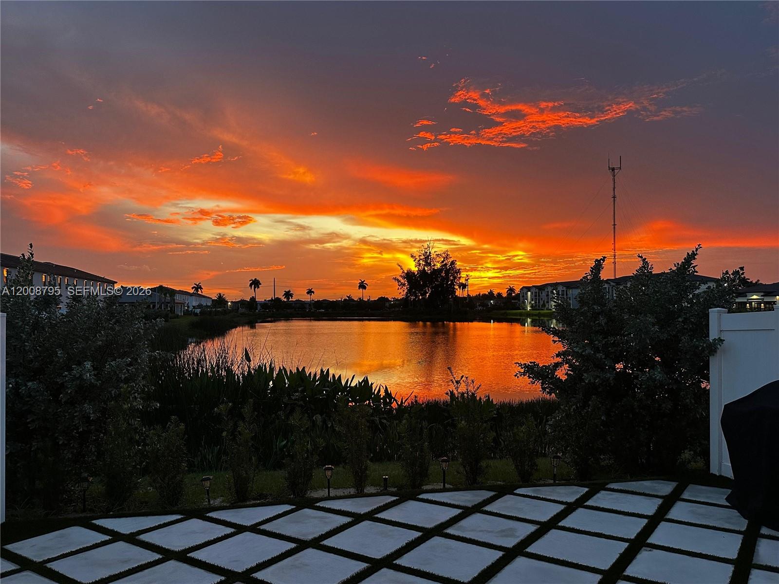A view of a lake at sunset from a patio with a paved grid floor — 20478 NW 4th Ct, Miami Gardens FL 33169, MIAMI GARDENS, FL