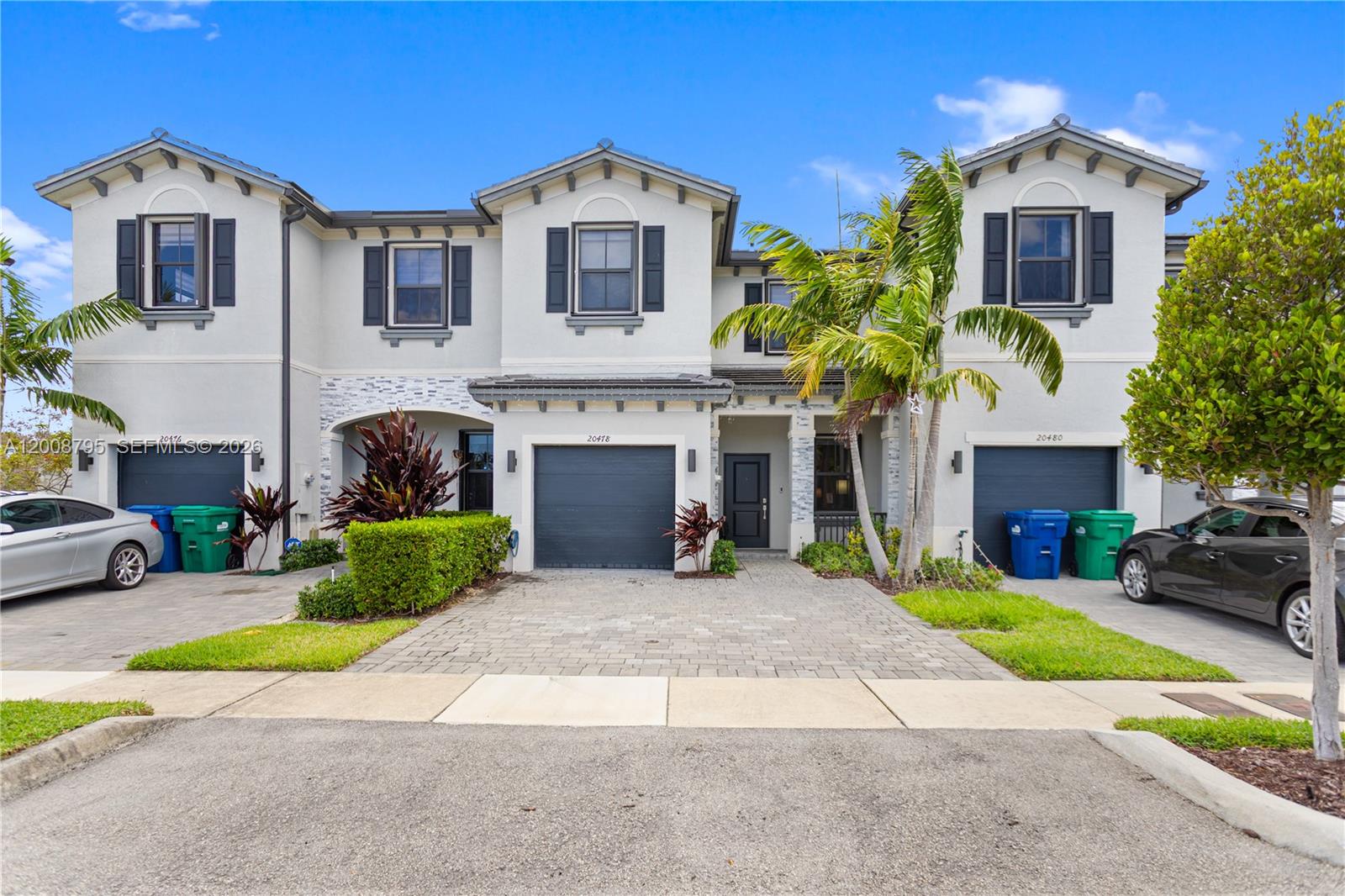 A row of three attached townhouses with gray garages, paved driveways, and palm trees — 20478 NW 4th Ct, Miami Gardens FL 33169, MIAMI GARDENS, FL